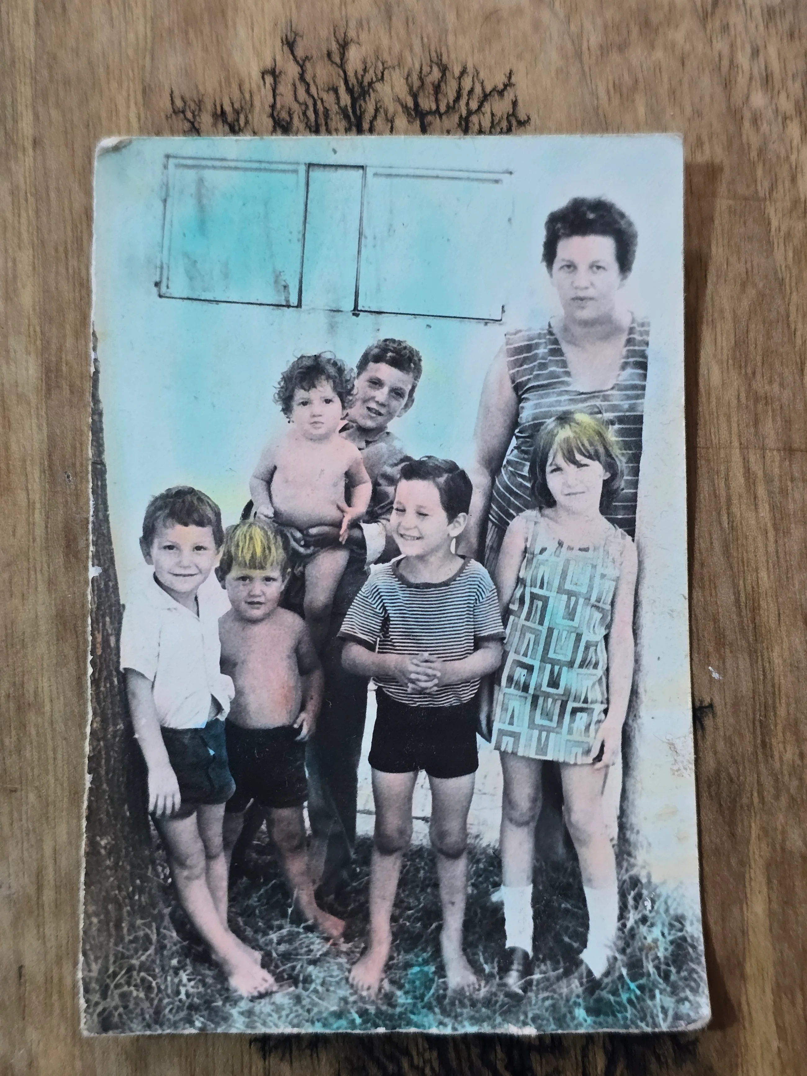 תצלום משפחתי ישן בשחור-לבן, אם וששה ילדים, מודבק על לוח עץ בלוי